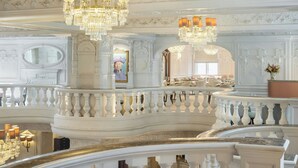 Ein prächtiger, reich verzierter Innenraum mit Kristallleuchtern, einem Balkon und klassizistischen architektonischen Details.