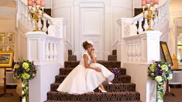A grand staircase with ornate railings and a woman in a wedding dress sitting on the steps.