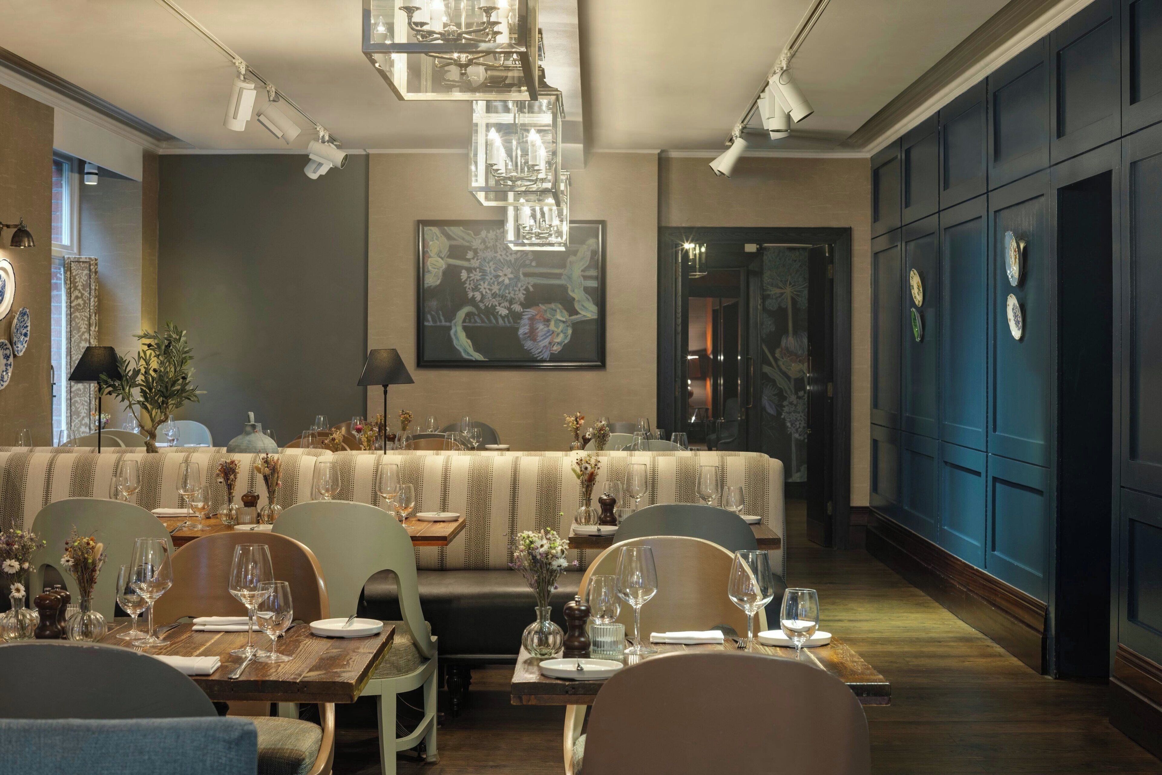Restaurante com balcão extenso, cabines e teto alto com luminárias pendentes.