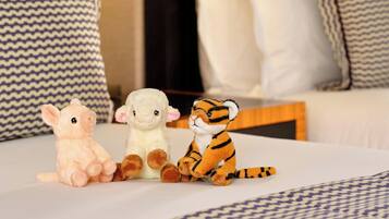 Three plush toys on a bed with patterned pillows.
