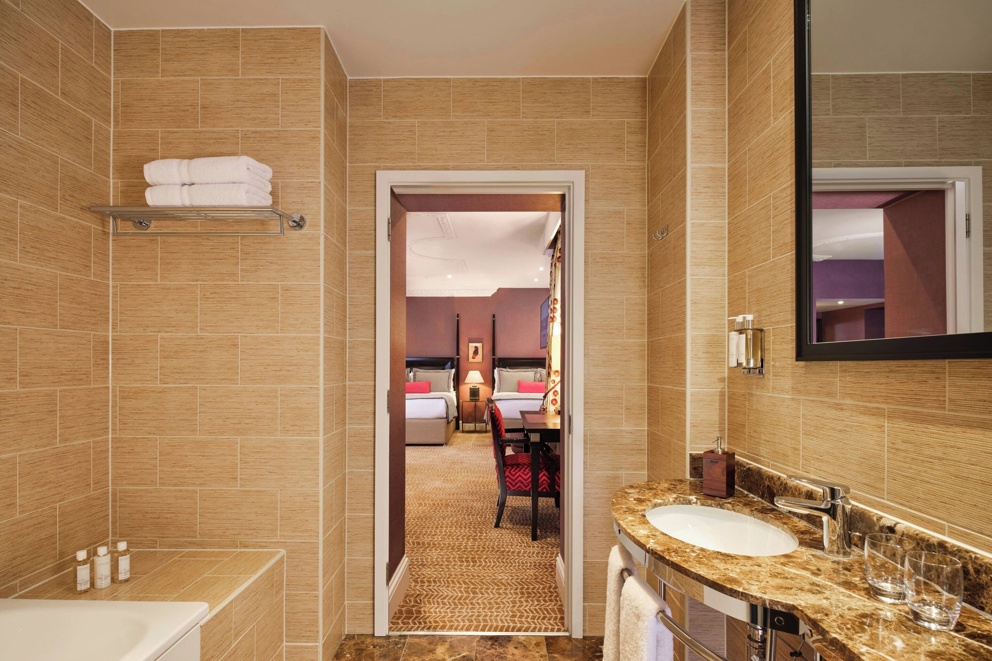 A hotel bathroom with a shower, sink, and a towel rack.