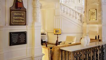 A grand staircase with ornate railings and a plaque commemorating the Houses of Parliament Division Bell.