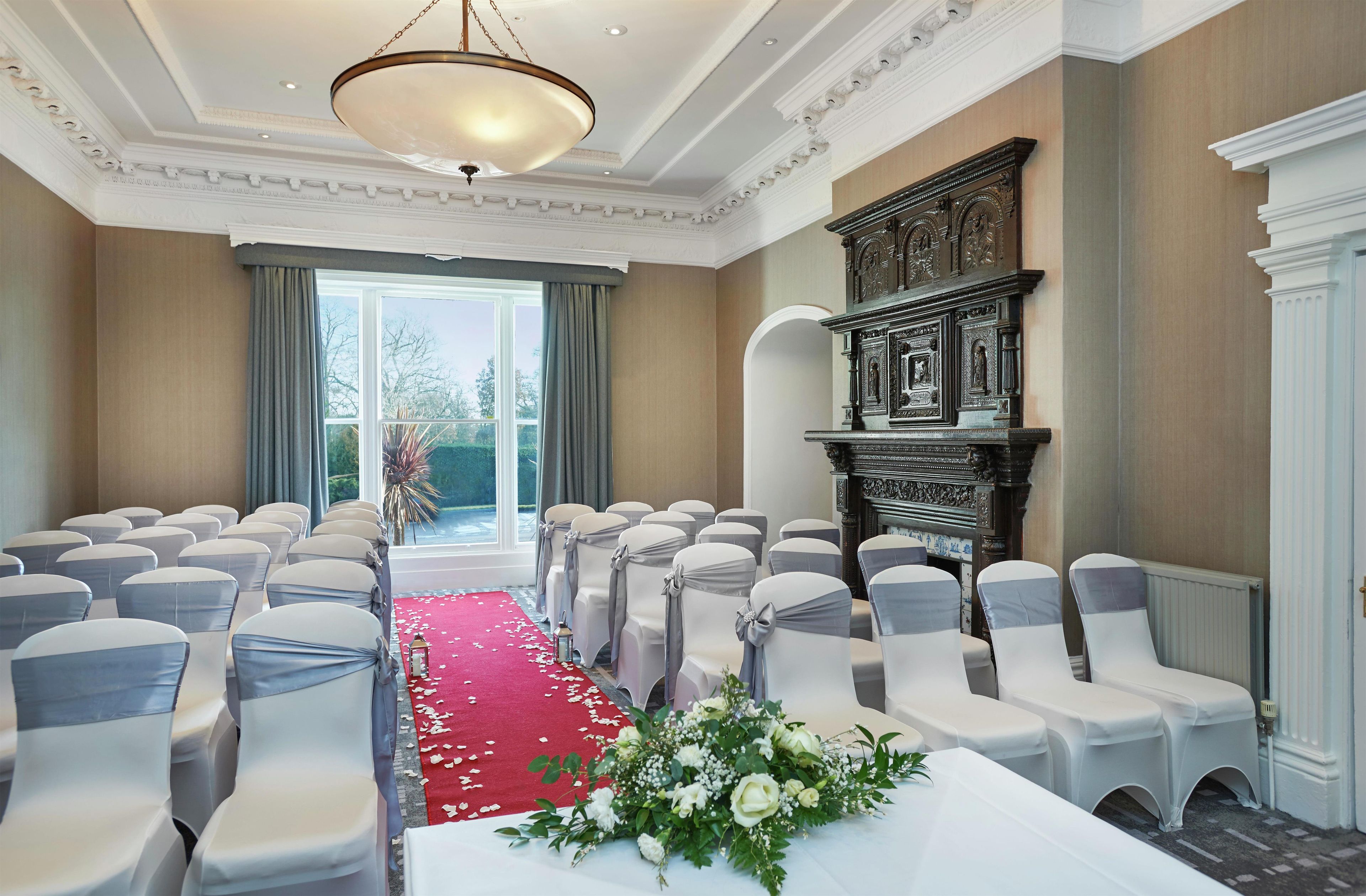 A conference room with rows of chairs, a red carpet, and a decorative fireplace.