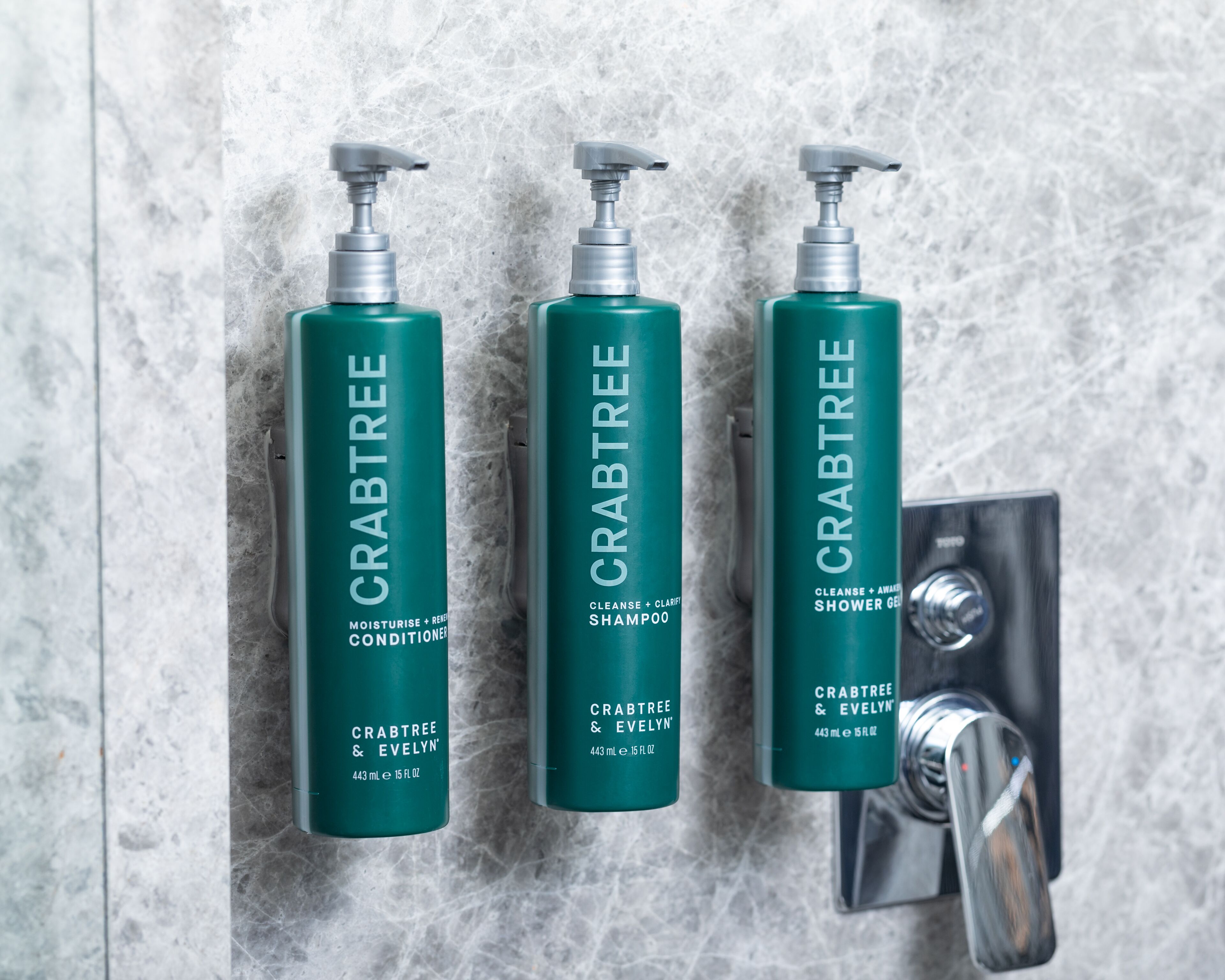 Three bottles of Crabtree & Evelyn products on a marble wall.