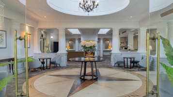 A spacious lobby with a central round table, seating arrangements, and a chandelier.