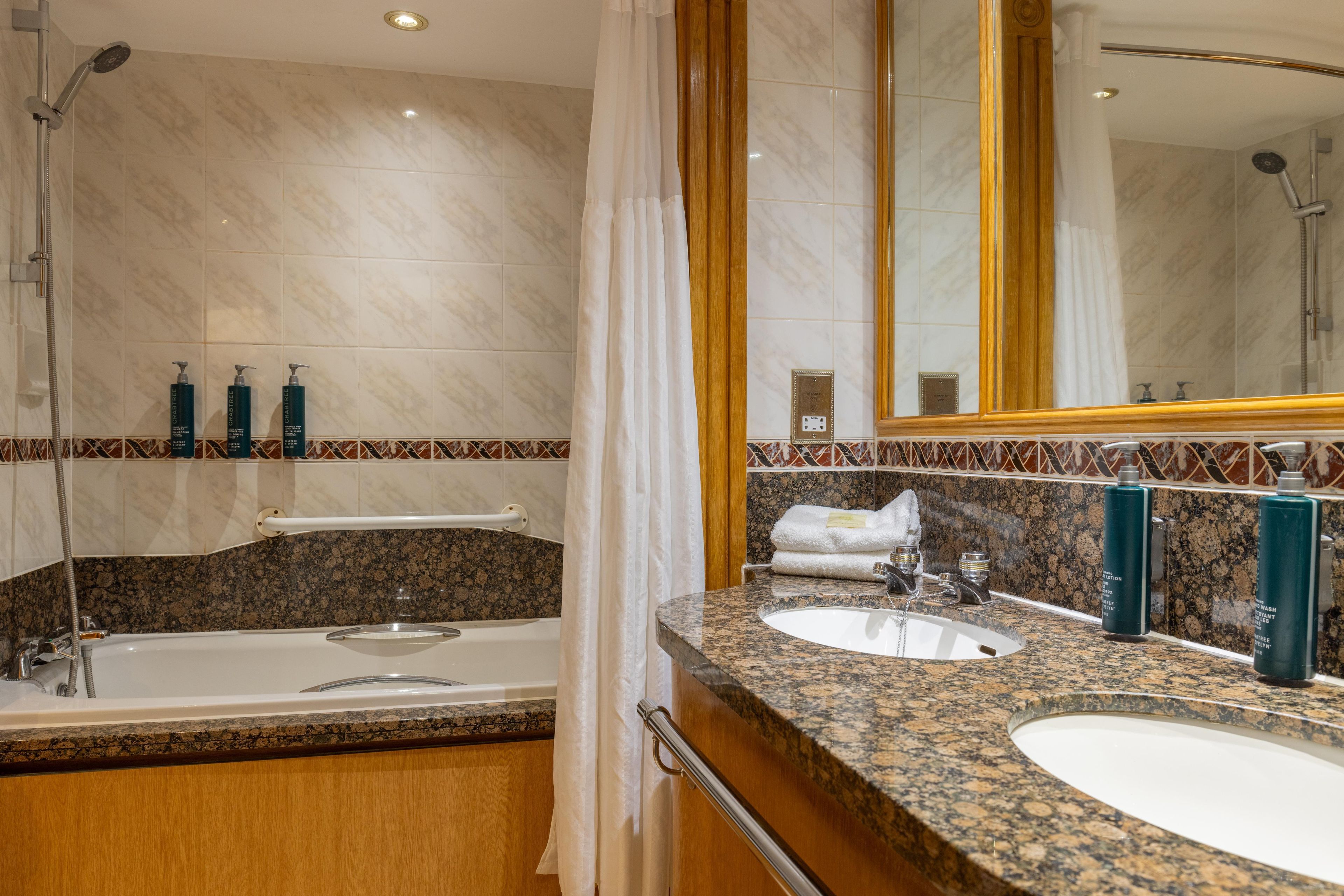 Un baño con bañera, dos lavamanos y un espejo grande.