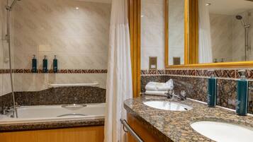 Un baño con bañera, dos lavamanos y un espejo grande.