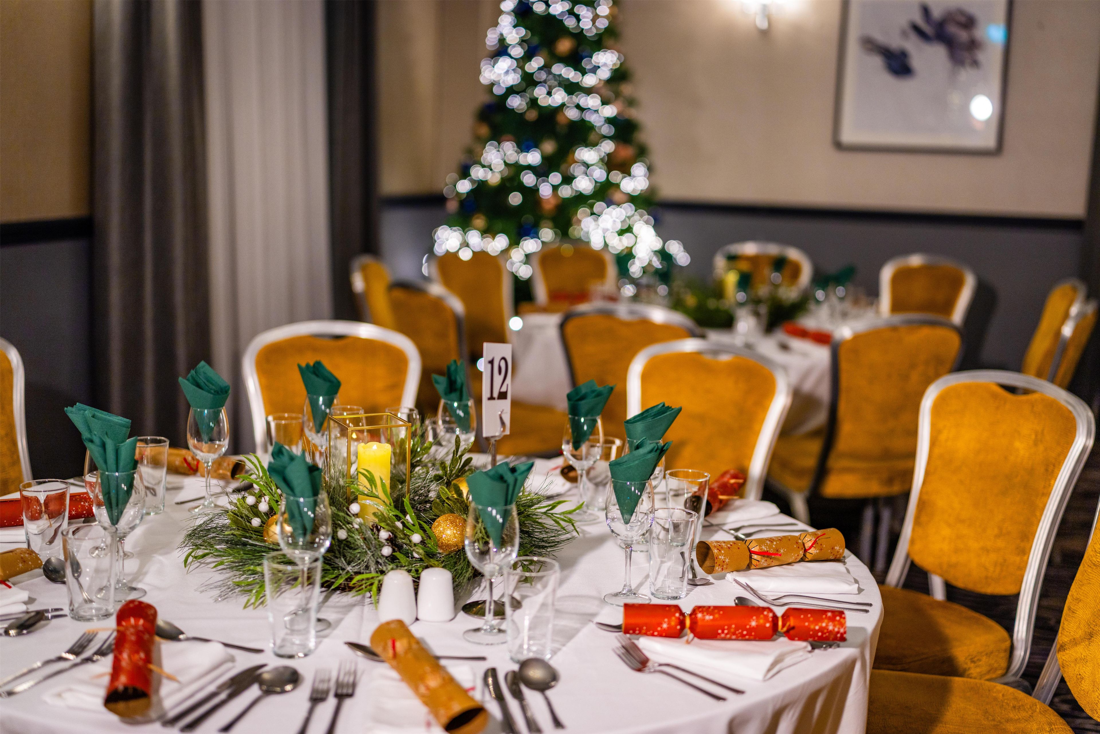 A dining table set with numbered place settings, glasses, cutlery, and festive decorations.