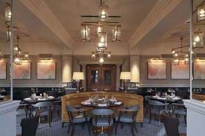A formal dining area with a central round table, multiple chairs, and pendant lighting.