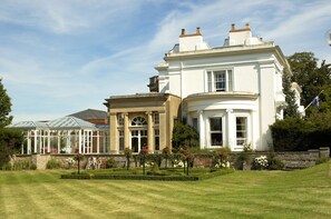A large, white, two-story building with a conservatory, surrounded by a well-manicured garden and a stone wall. - Hilton Puckrup Hall Hotel & Golf Club, Tewkesbury (Tewkesbury)