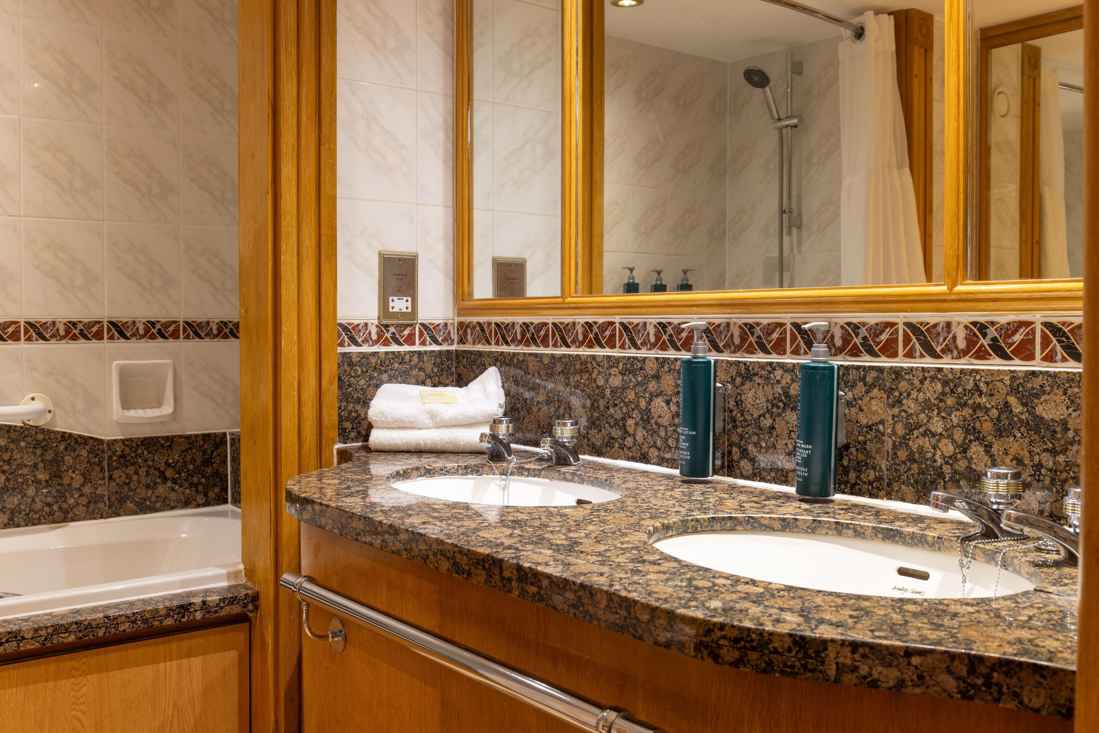 A bathroom with two sinks, a large mirror, and a shower.