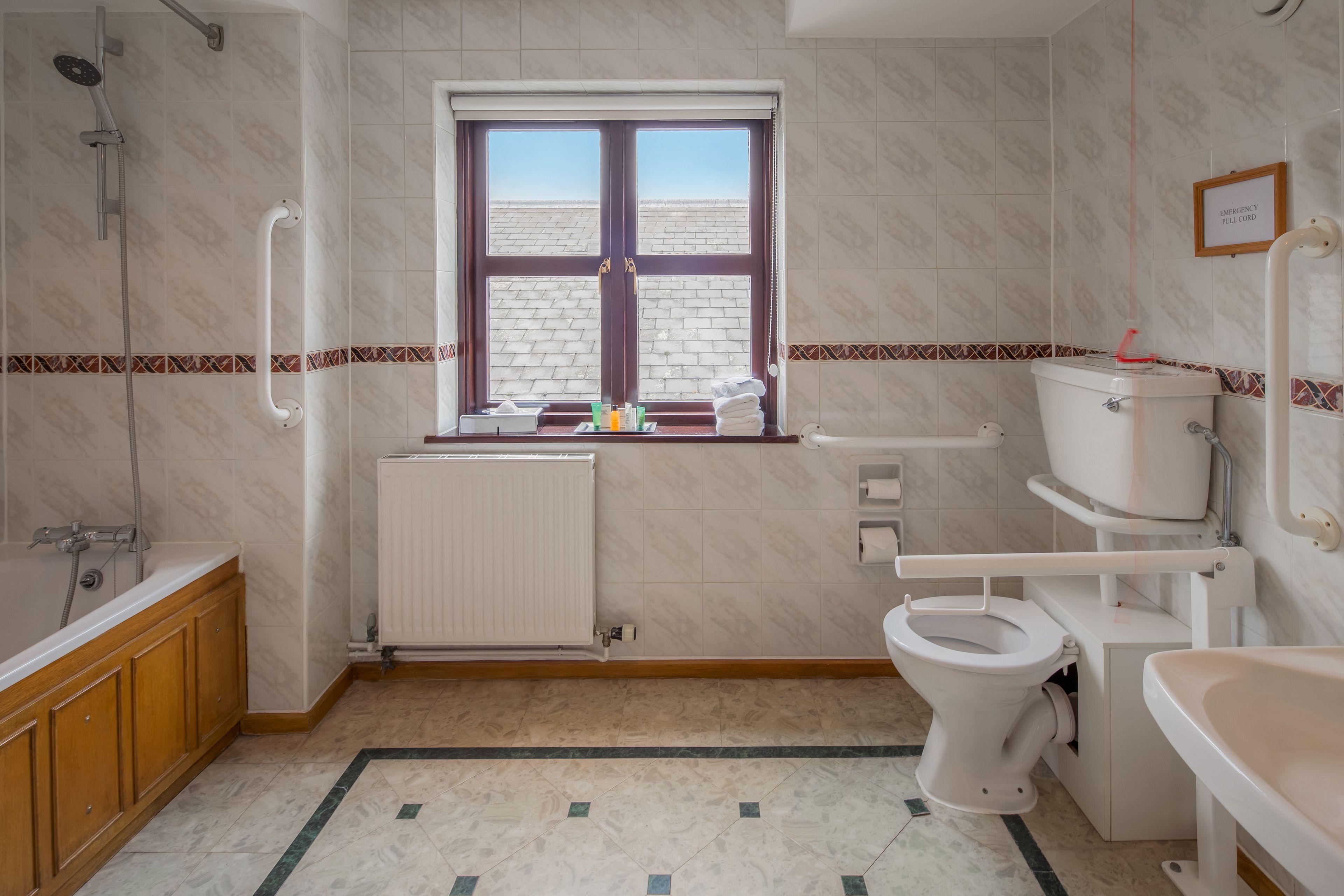 Un baño con inodoro, lavabo, ducha y ventana.