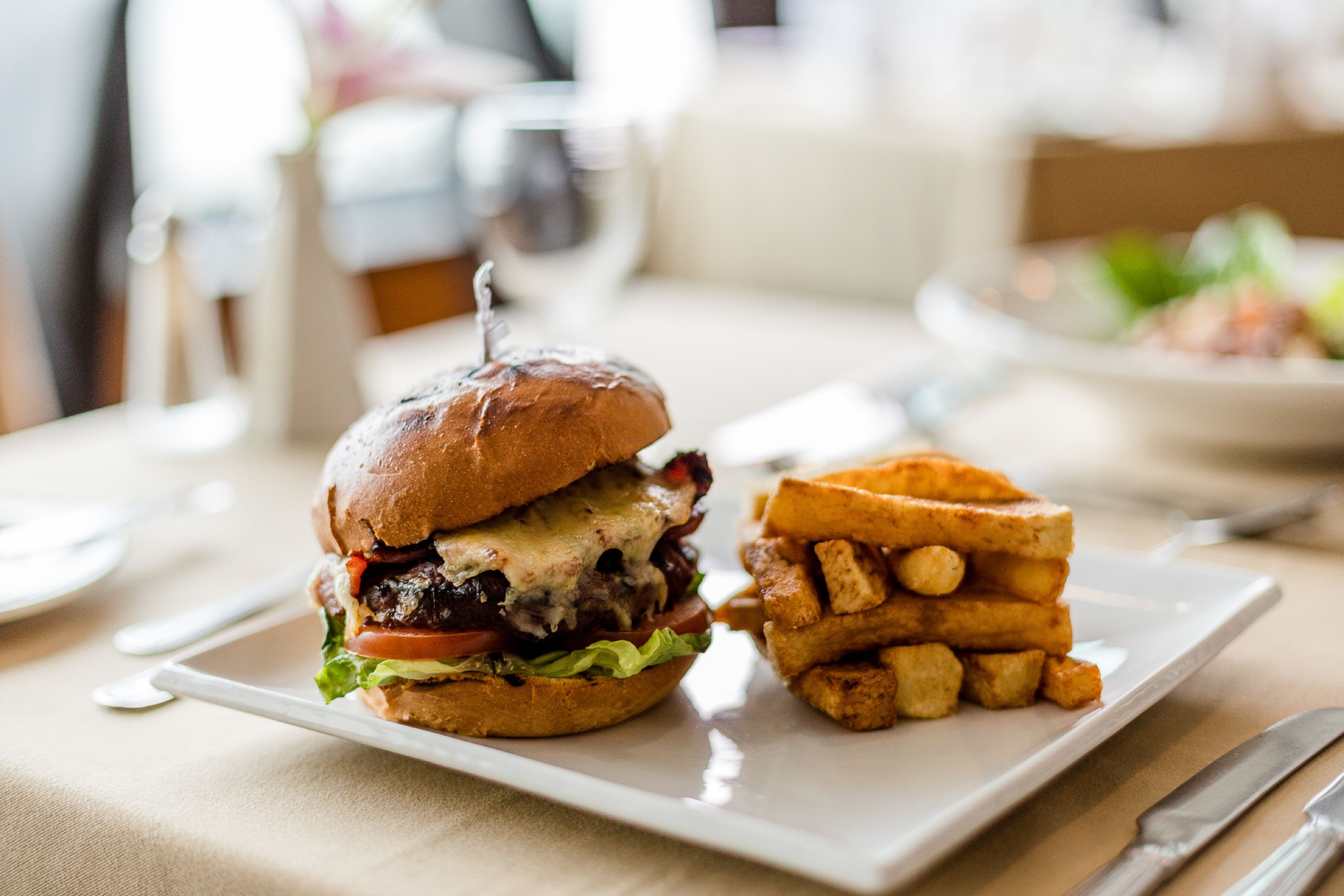 Un plato con una hamburguesa y papas fritas sobre una mesa.
