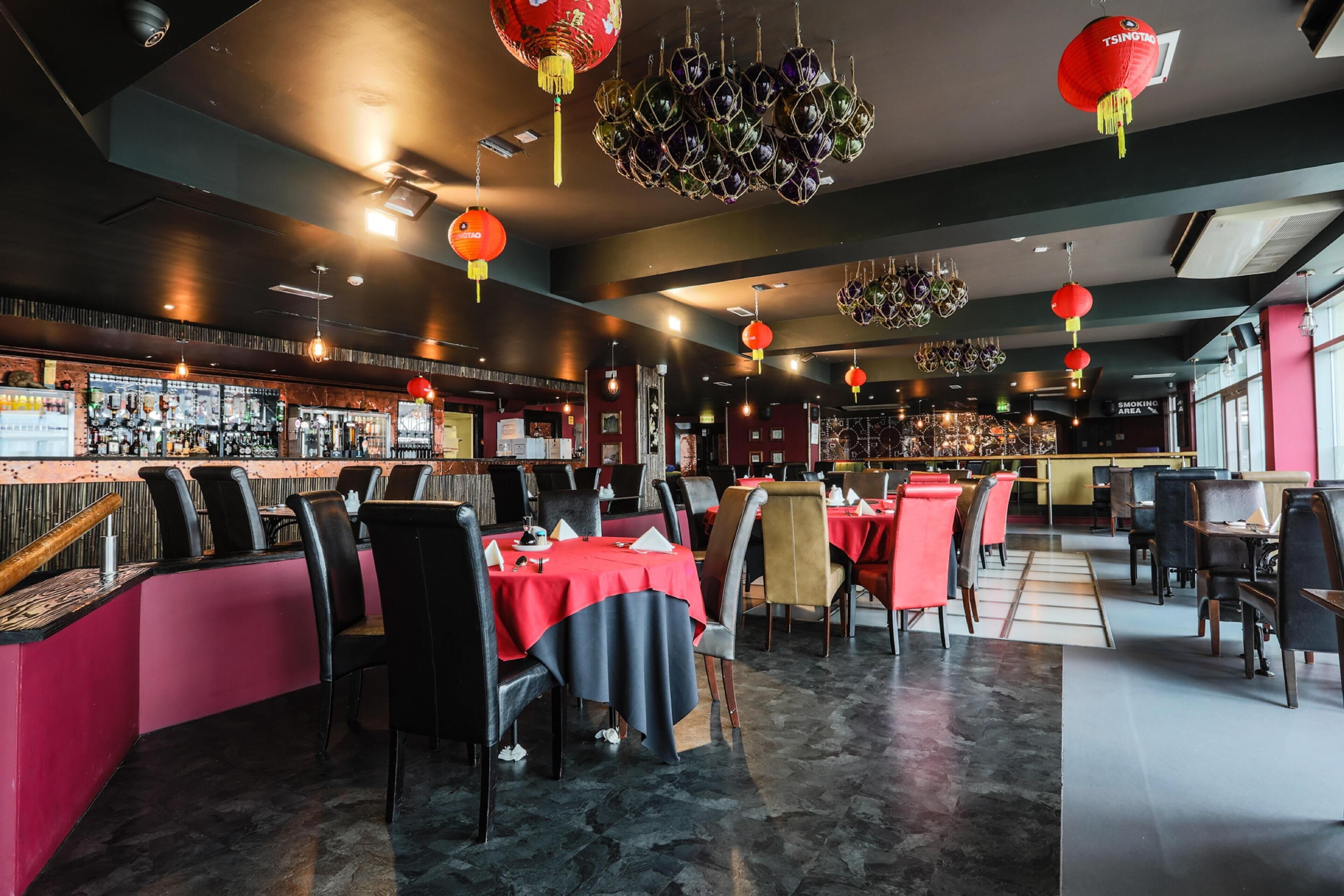 A restaurant with tables and chairs, a bar area, and hanging lanterns.