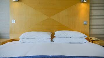 Ein Hotelzimmer mit einem großen Bett, zwei Nachttischen, einem Telefon und Wandleuchten.