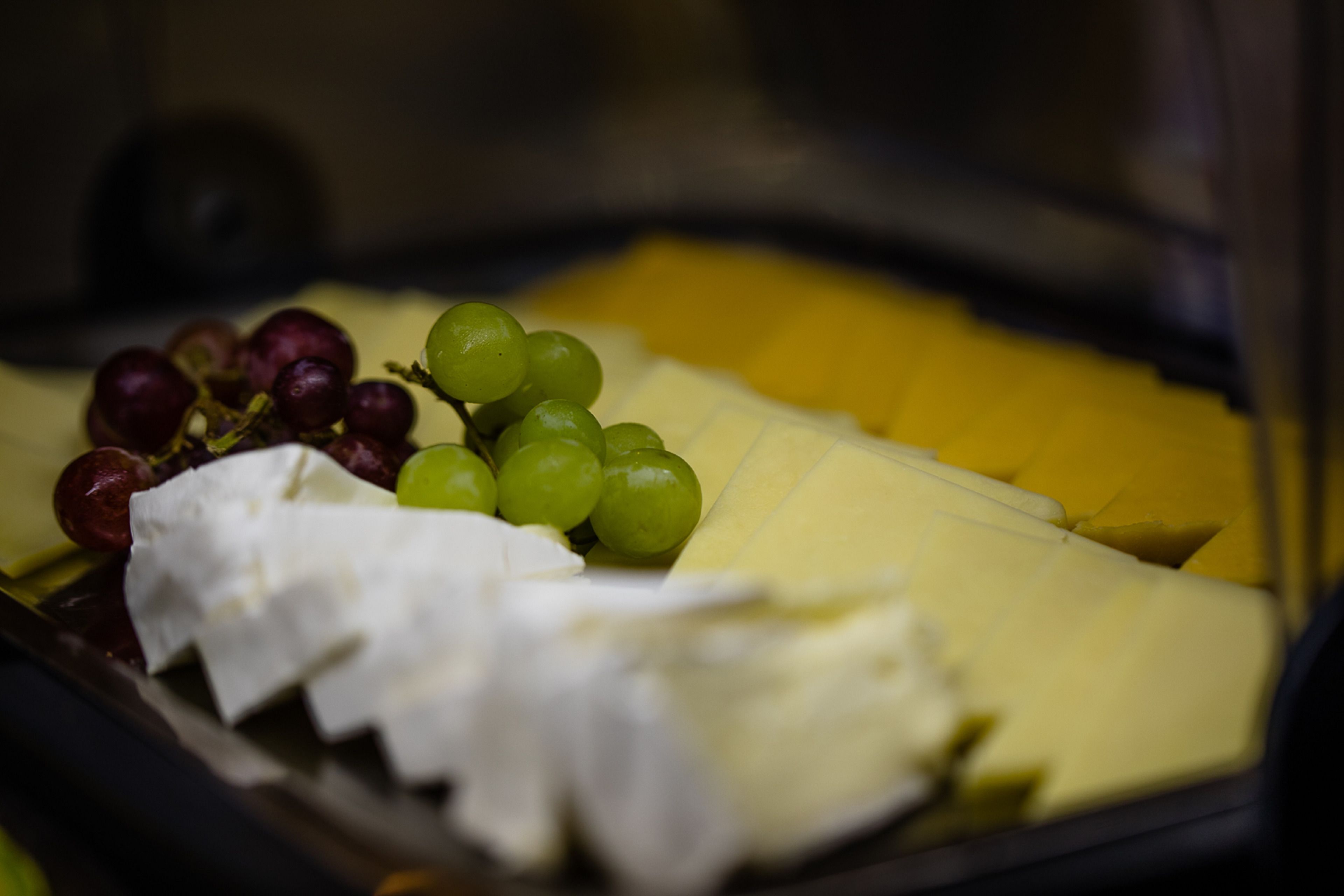 Un plateau de fromages accompagné de raisins et d’une banane.