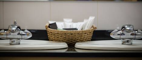 A bathroom with two sinks, a woven basket between them, and a mirror reflecting the room.