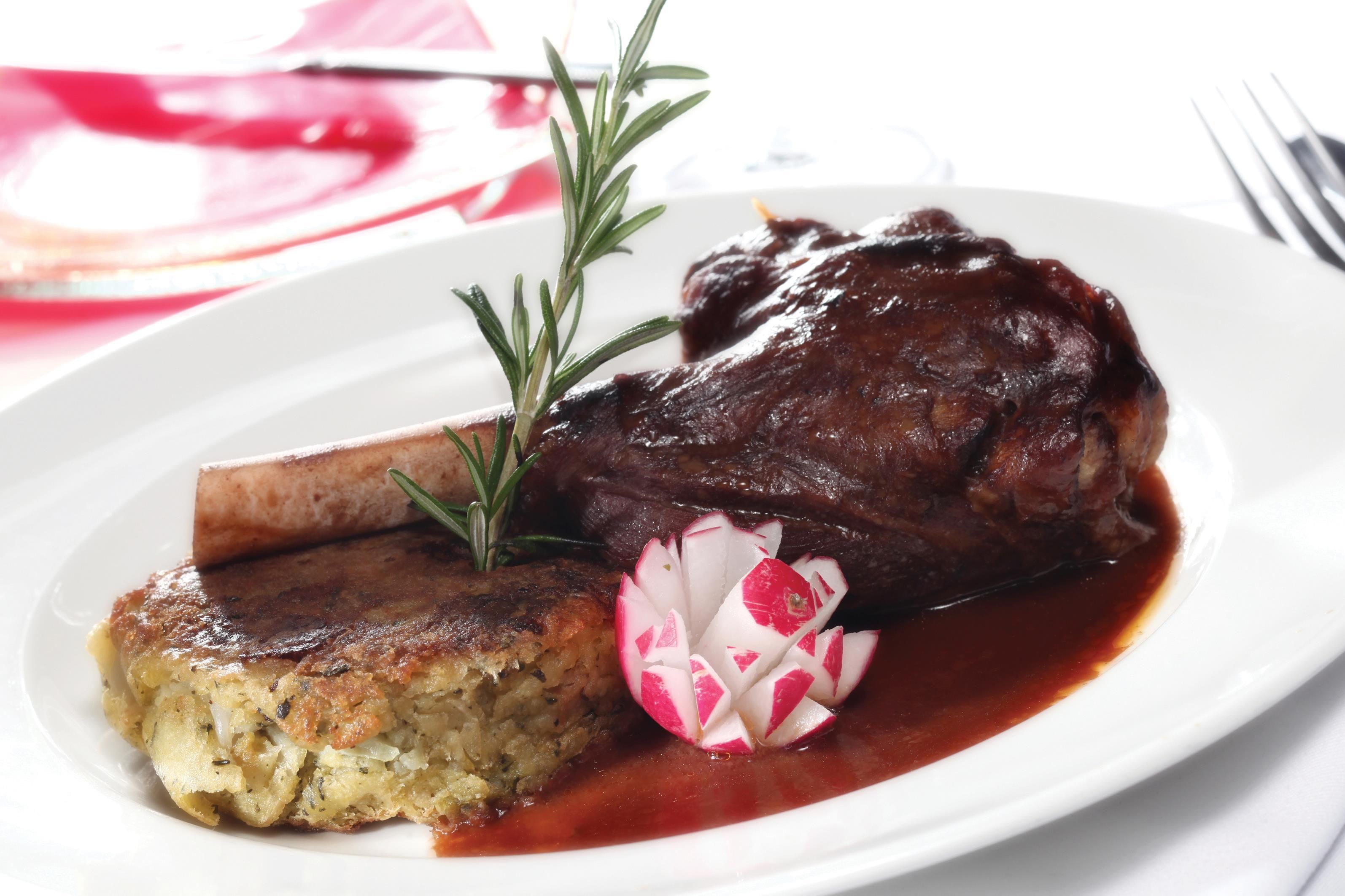 A plate with a piece of meat, a slice of bread, and a garnish of radish and rosemary.