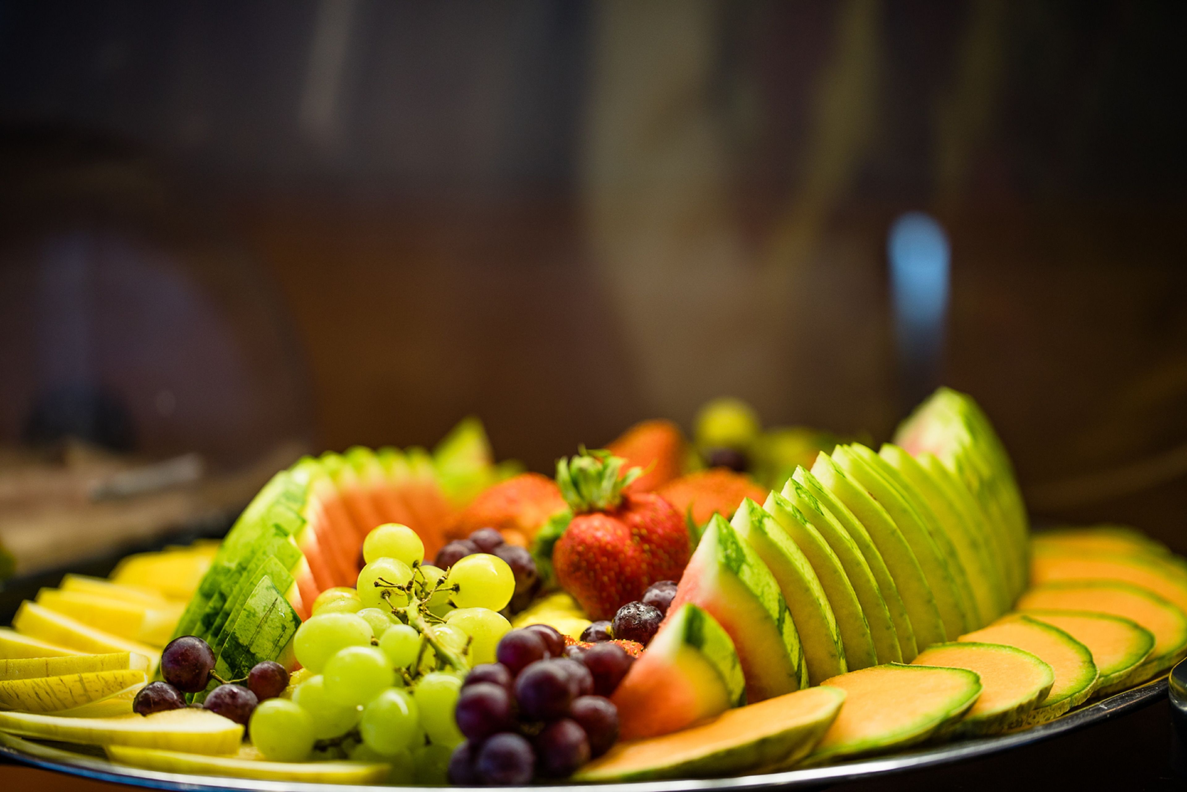 Una bandeja de frutas con rodajas de manzana, uvas, fresas y aguacate.