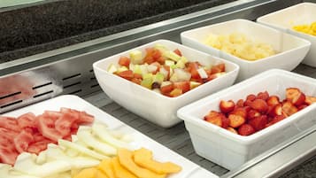 Un bufé con diversas frutas, incluyendo sandía, manzanas y fresas.