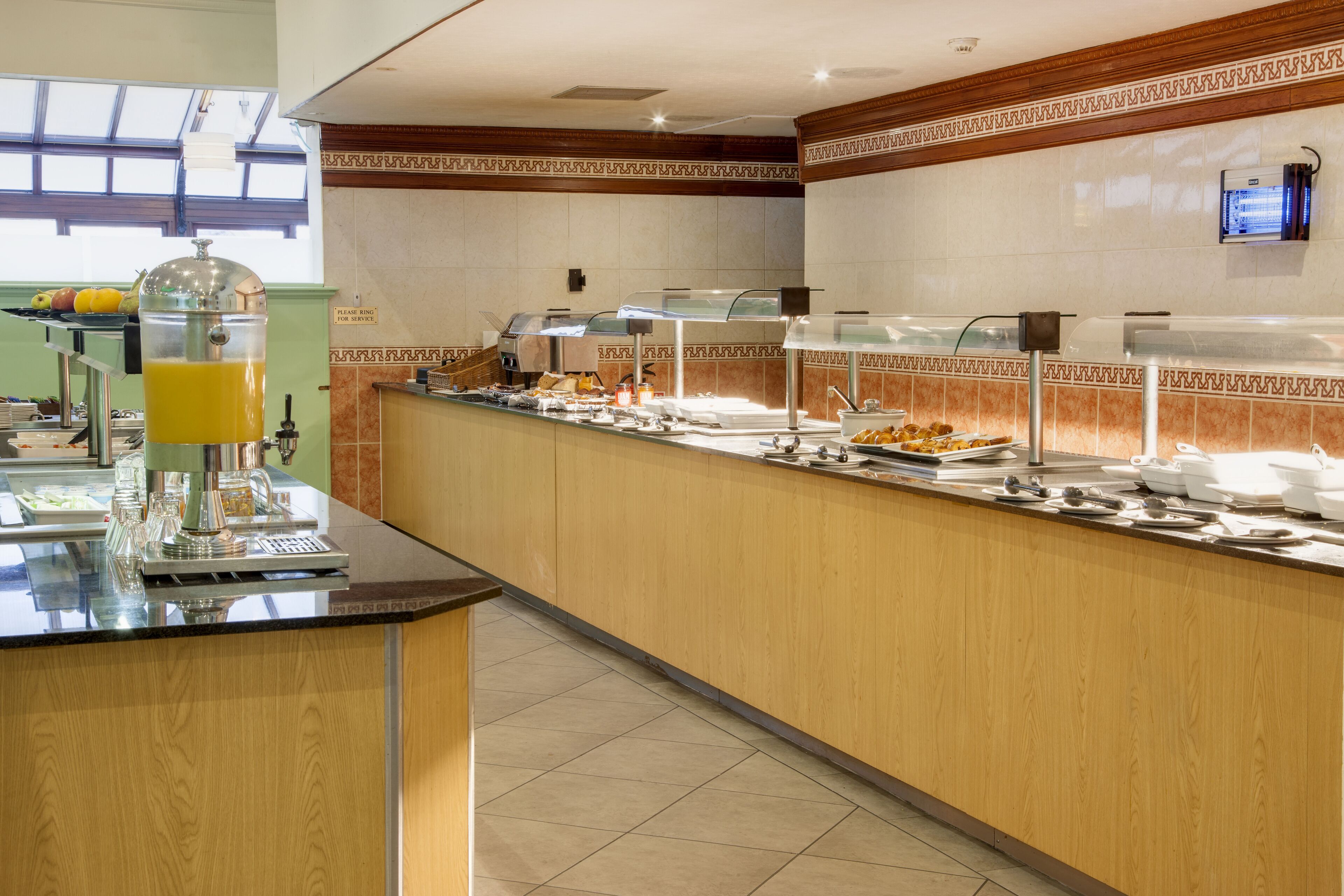 Un buffet avec un distributeur de jus, divers plats et un espace de libre-service.