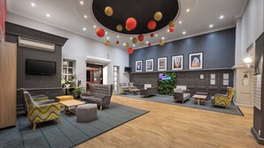 A spacious lobby with a modern design, featuring a variety of seating options, a fireplace, and a wall adorned with framed pictures.