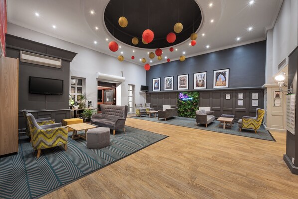 A spacious lobby with a modern design, featuring a variety of seating options, a fireplace, and a wall adorned with framed pictures.