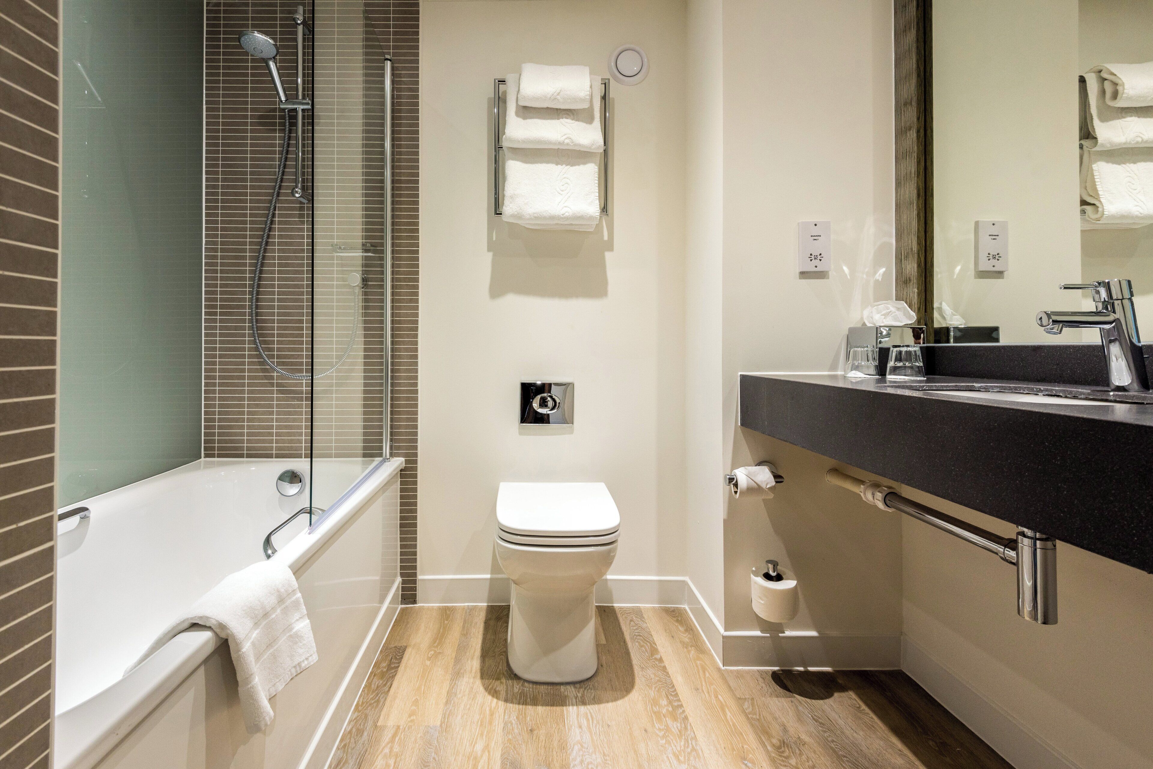 A modern bathroom with a bathtub, toilet, and a large mirror.