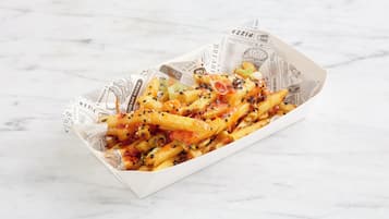 A box of fries with various toppings and a newspaper lining.