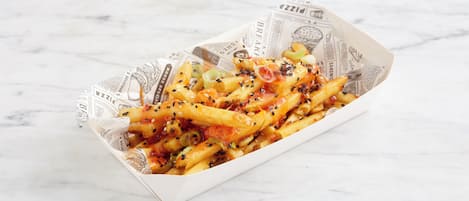 A box of fries with various toppings and a newspaper lining.