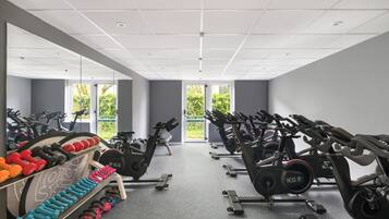 Une salle de sport équipée de vélos d’appartement, d’haltères et de kettlebells.