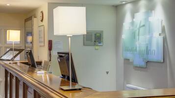 A reception desk with a computer, a lamp, and a wall-mounted sign.