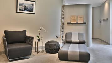 Et moderne loungeområde med sofa, lænestol og et lille bord med en potteplante.