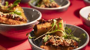 A series of dishes with a focus on a bowl containing a piece of food garnished with sesame seeds and greens.
