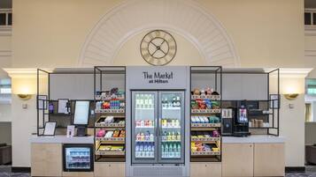 Un petit magasin proposant des produits destinés aux clients d’hôtel, avec une horloge au-dessus, et où l’on trouve des boissons et des en-cas.