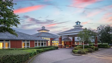 Traditional hotel with a central entrance and two wings, featuring a covered walkway and parking area.