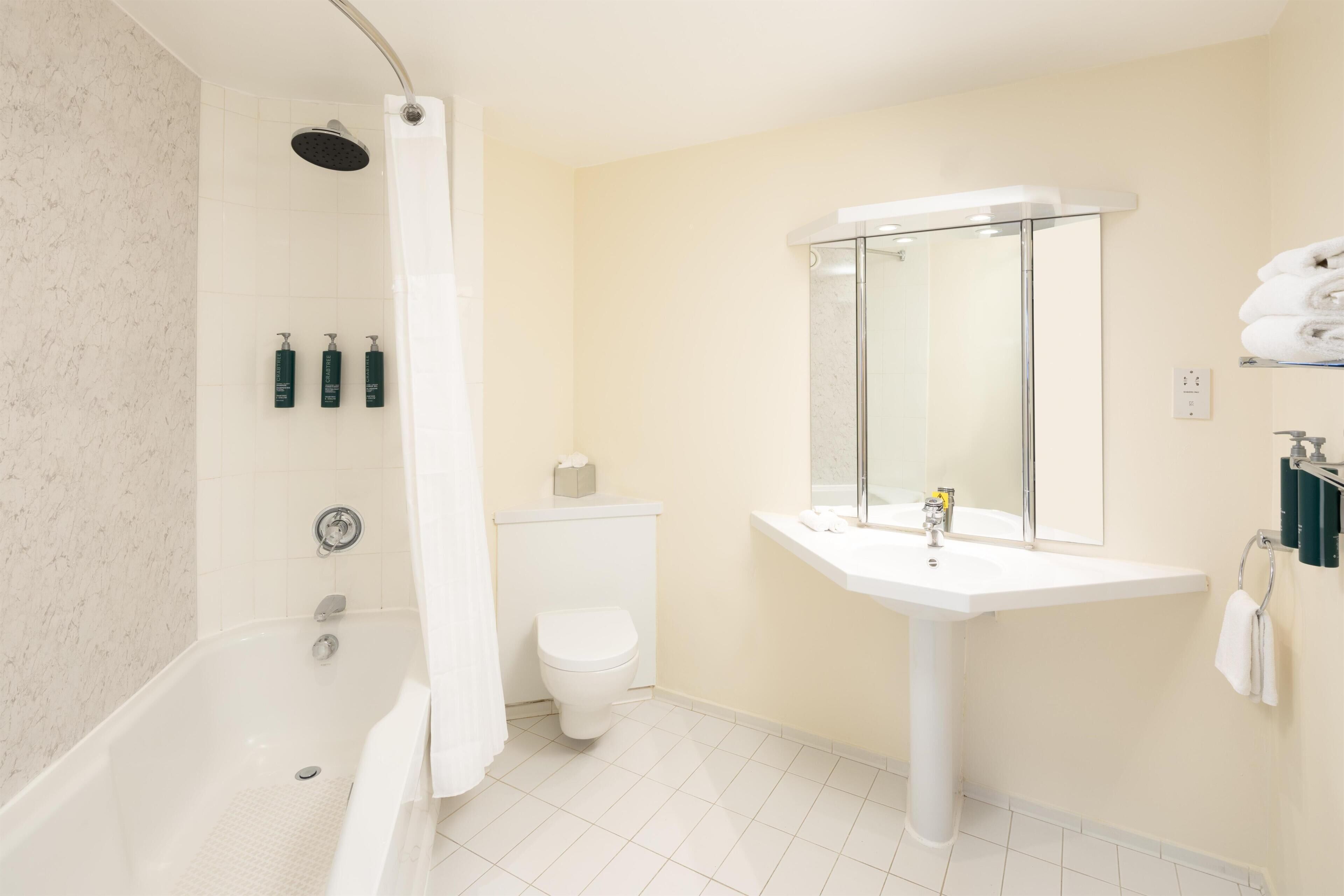 A bathroom with a bathtub, toilet, sink, and a shower with a glass enclosure.