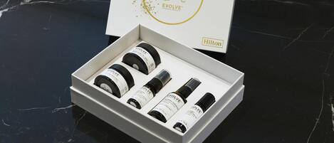 A white box with a gold logo and text, containing four black bottles and a white box with text.