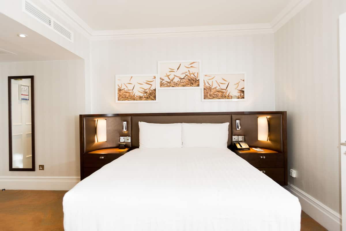 Una camera d'albergo con un letto grande, due comodini con lampade e tre opere d'arte appese alla parete.
