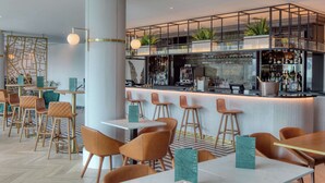 Un área de bar moderna con taburetes altos, una barra con refrigerador de vinos y un llamativo mural con un mapa.