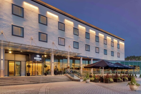 Welcome to our hotel, featuring a modern design with outdoor seating areas and a convenient parking facility.