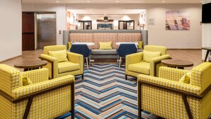 A hotel lobby with yellow patterned chairs, a central sofa with blue cushions, and a colorful zigzag carpet. - Hampton Inn by Hilton Irvine East - Lake Forest (Foothill Ranch)