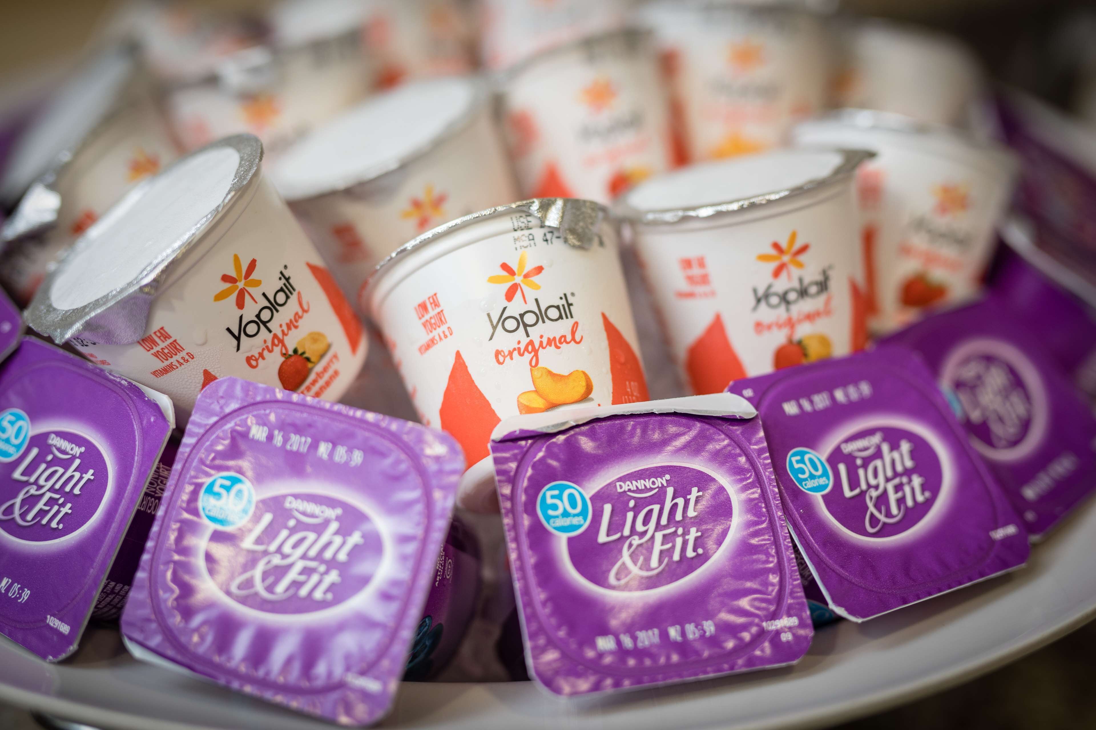 A variety of yogurt containers and light & fit snack packages on a plate.