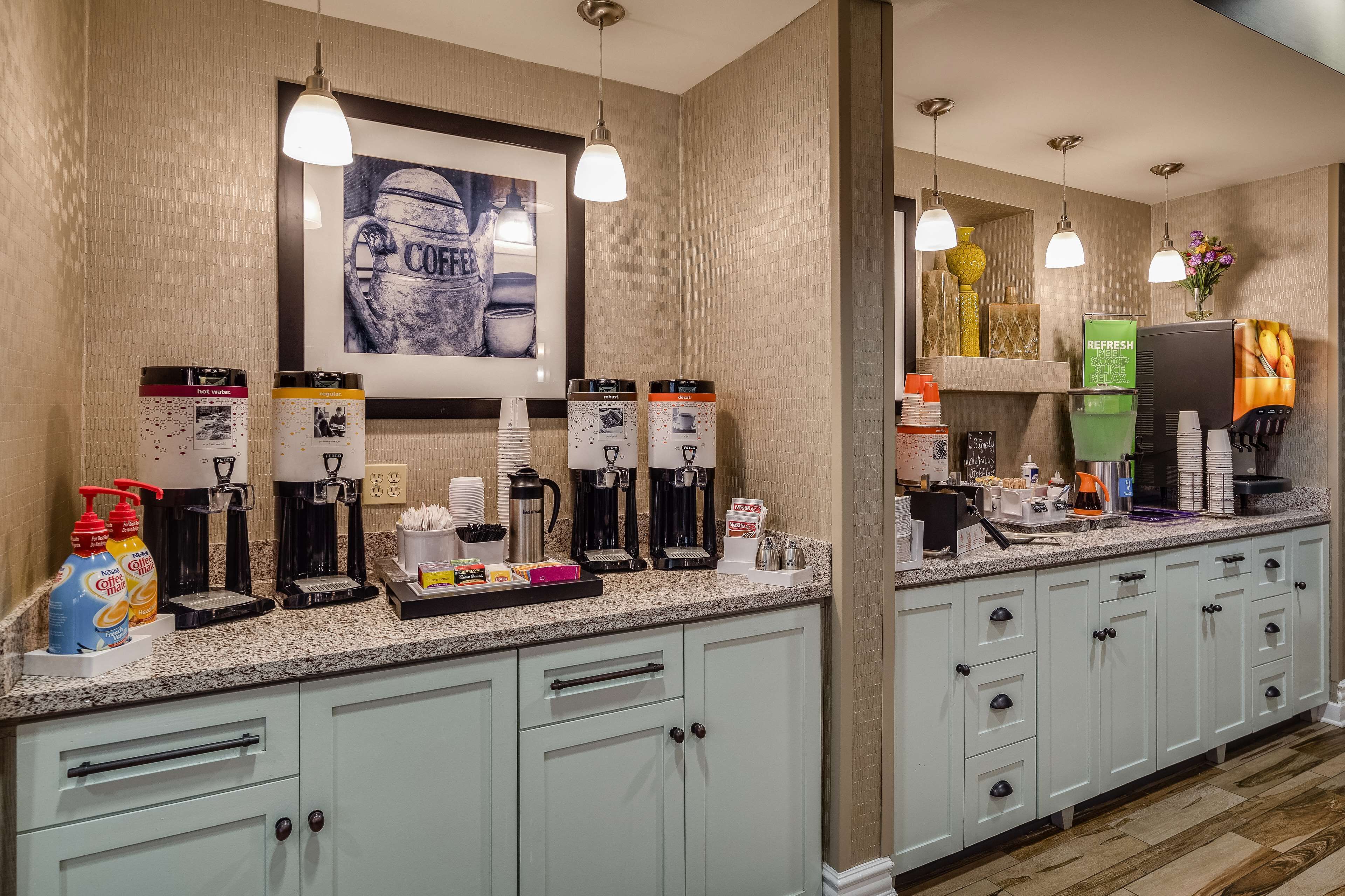 Una cocina de hotel con varias cafeteras, una estación de café y un cuadro en la pared.