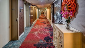A hotel hallway with an elevator, a red carpet, and a decorative wall piece. - Hampton Inn San Francisco Airport (South San Francisco)