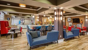 A hotel lobby with seating areas, a reception desk, and a bar. - Hampton Inn San Francisco Airport (South San Francisco)