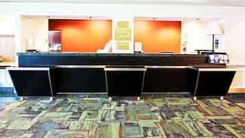 A hotel reception area with a check-in counter, a continental breakfast sign, and a no-pets policy notice.