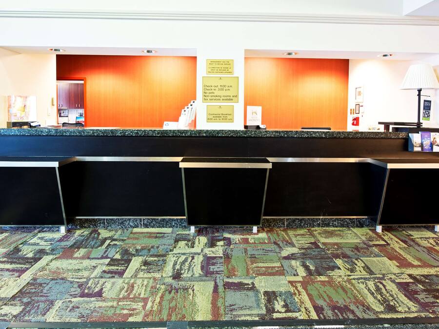 A hotel reception area with a check-in counter, a continental breakfast sign, and a no-pets policy notice.