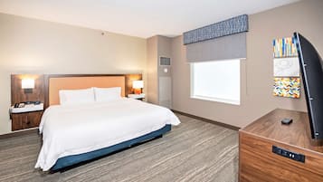 Una habitación de hotel con una cama grande, lámparas de noche, un televisor de pantalla plana, un escritorio y una ventana.