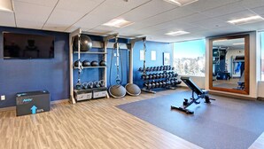 Une salle de sport équipée de matériel d’exercice, dotée d’un miroir et offrant une vue sur l’extérieur.